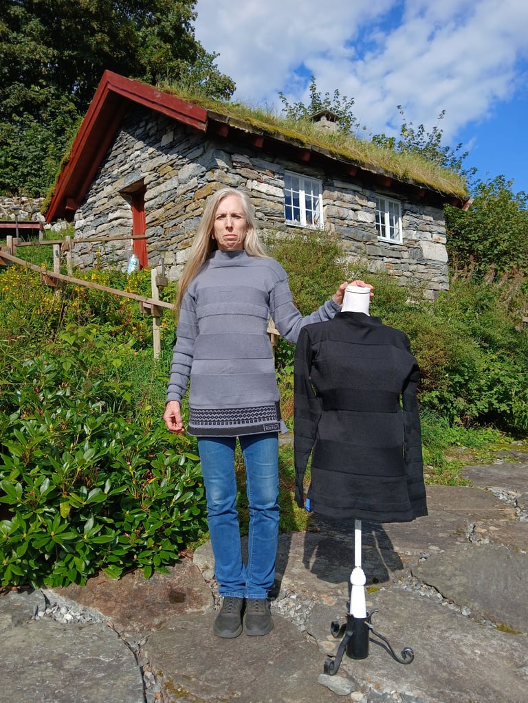 Woman in gray sweater standing next to dress form outside rustic stone cottage with moss roof