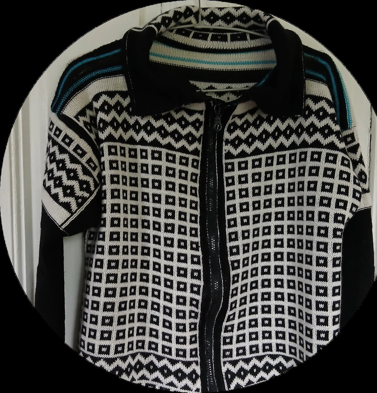 Black and white patterned cardigan sweater with geometric designs and contrasting black trim displayed on a hanger